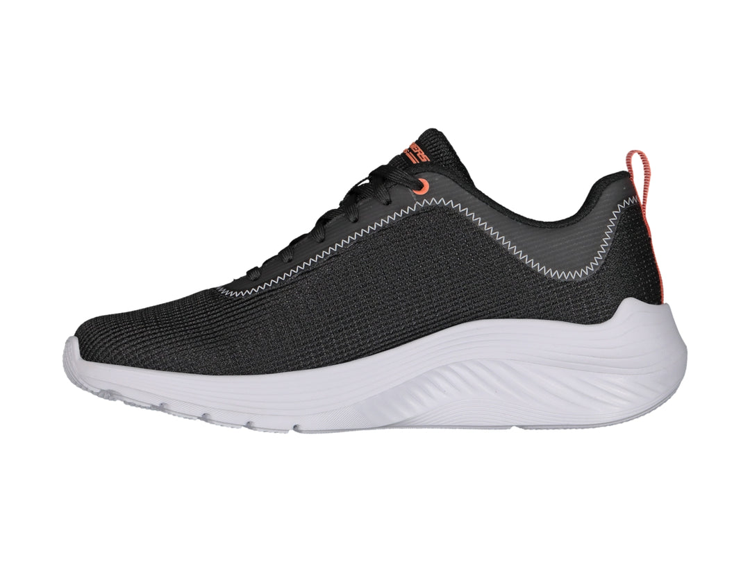 Tenis deportivos Skechers color negro con suela blanca y detalle naranja en el talón.
