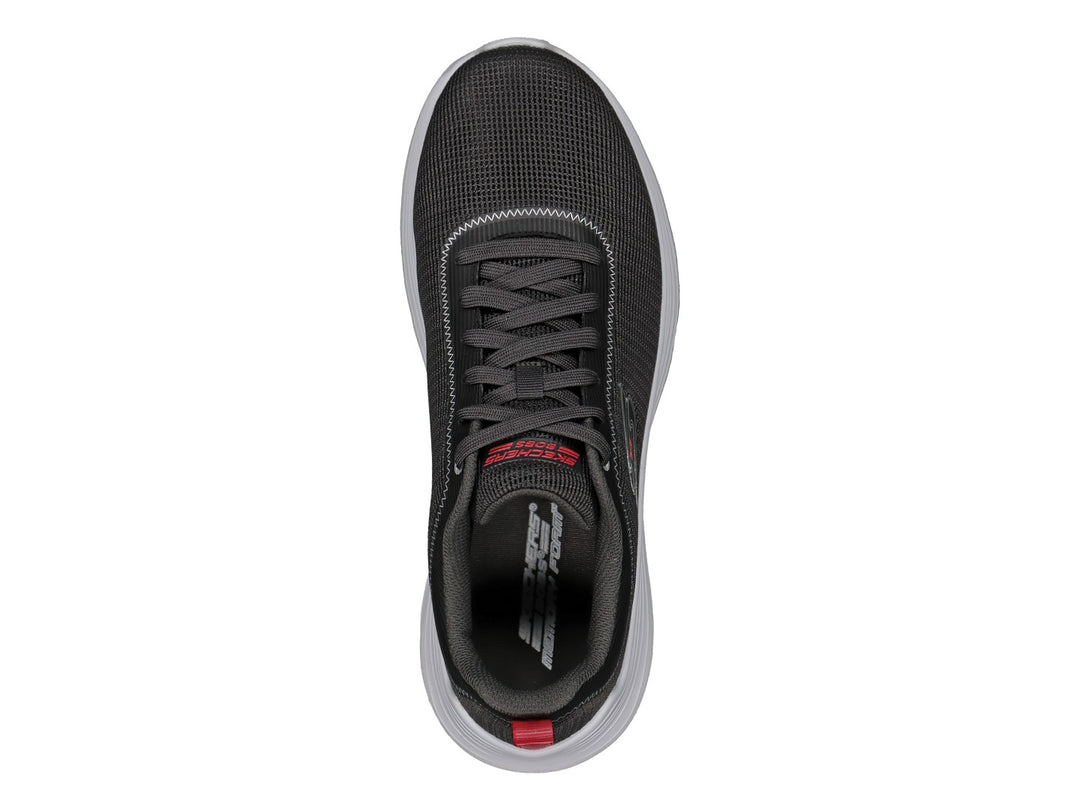 Tenis Skechers color gris con suela blanca y pequeña pestaña roja en el talón.