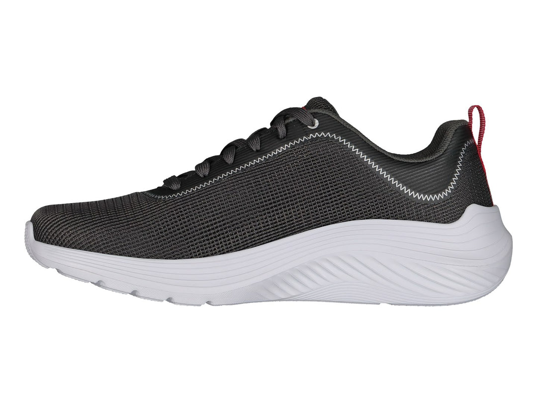 Tenis Skechers color gris con suela blanca y pequeña pestaña roja en el talón.