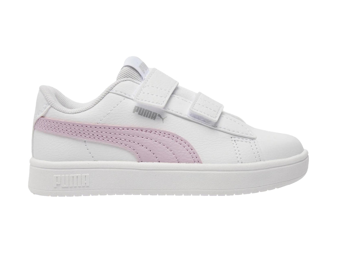 Tenis PUMA blancos con franja morada lateral y cierre de velcro.