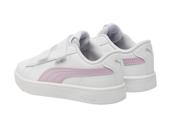 Tenis PUMA blancos con franja morada lateral y cierre de velcro.