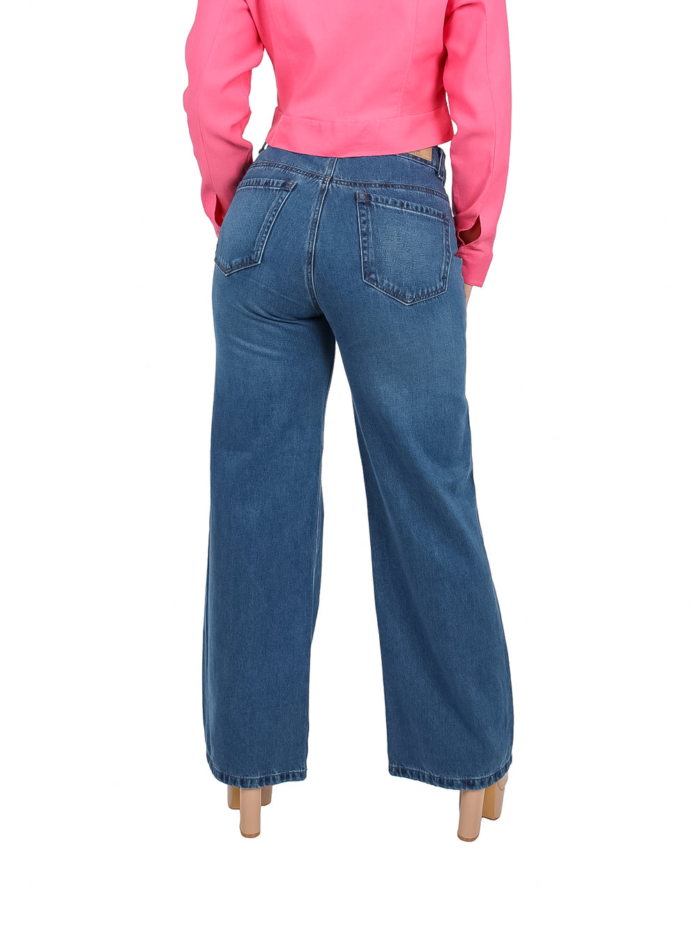 Mujer vistiendo jeans azules de pierna ancha y chaqueta corta rosa.