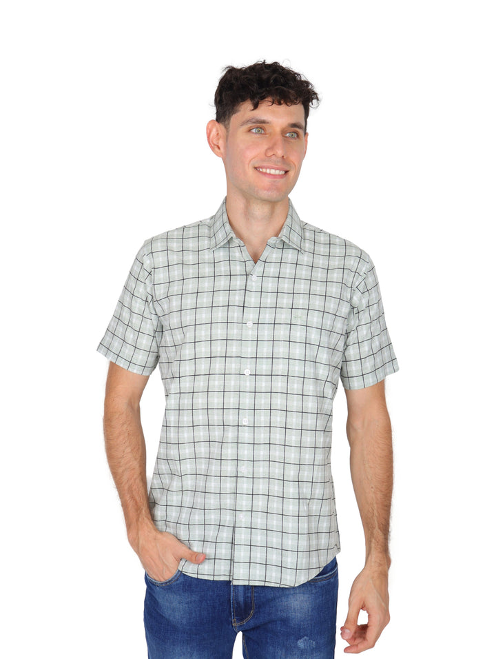 Hombre vistiendo una camisa blanca de manga corta con estampado de cuadros negros y pantalones jeans azules.