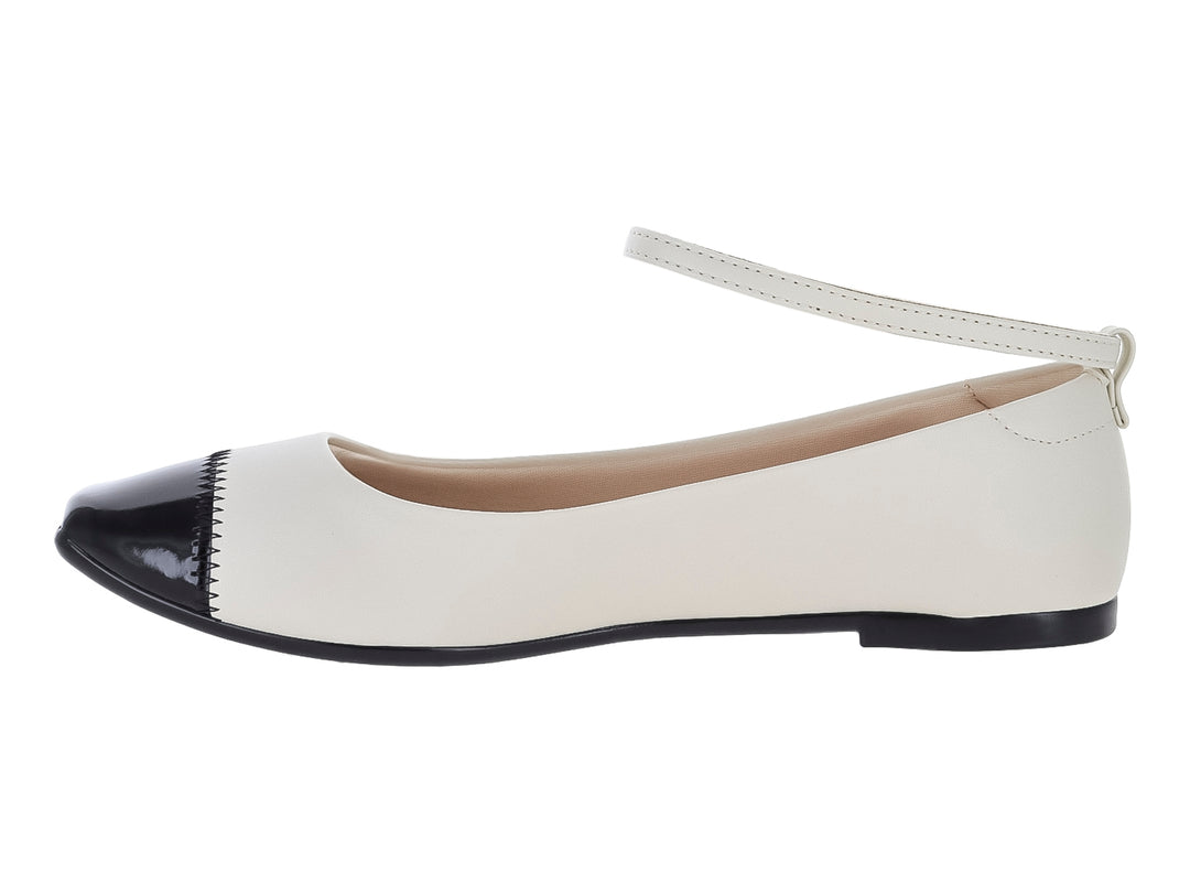 Zapato plano Moleca color blanco con punta negra brillante y correa ajustable al tobillo.
