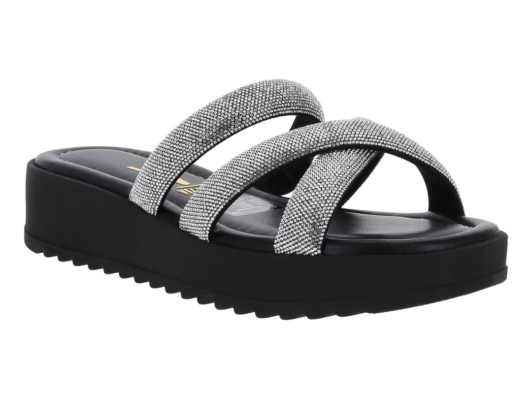 Sandalia de plataforma negra con tiras cruzadas plateadas brillantes y suela dentada.