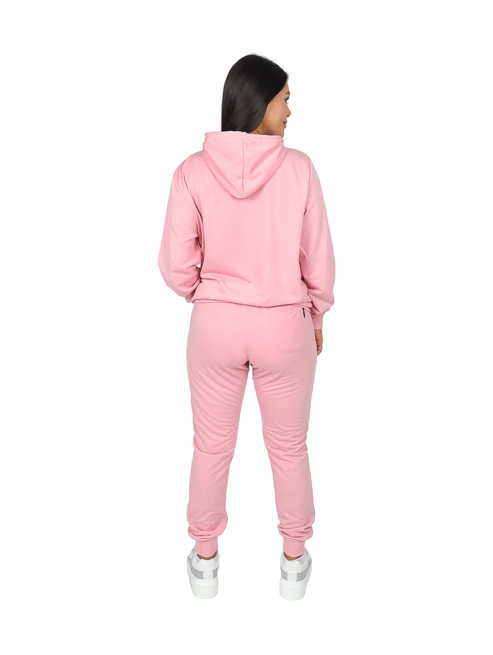 Mujer vistiendo un conjunto deportivo color salmón compuesto por sudadera con capucha y pants.