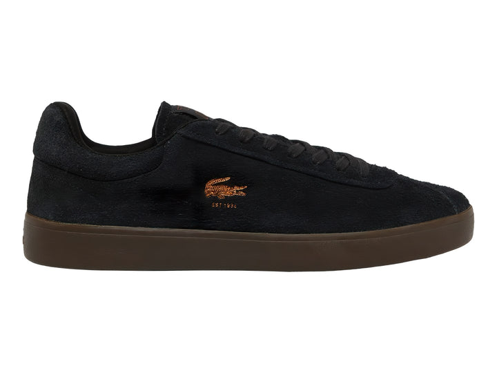 Tenis Lacoste de gamuza color negro con suela café y logotipo dorado en el lateral.