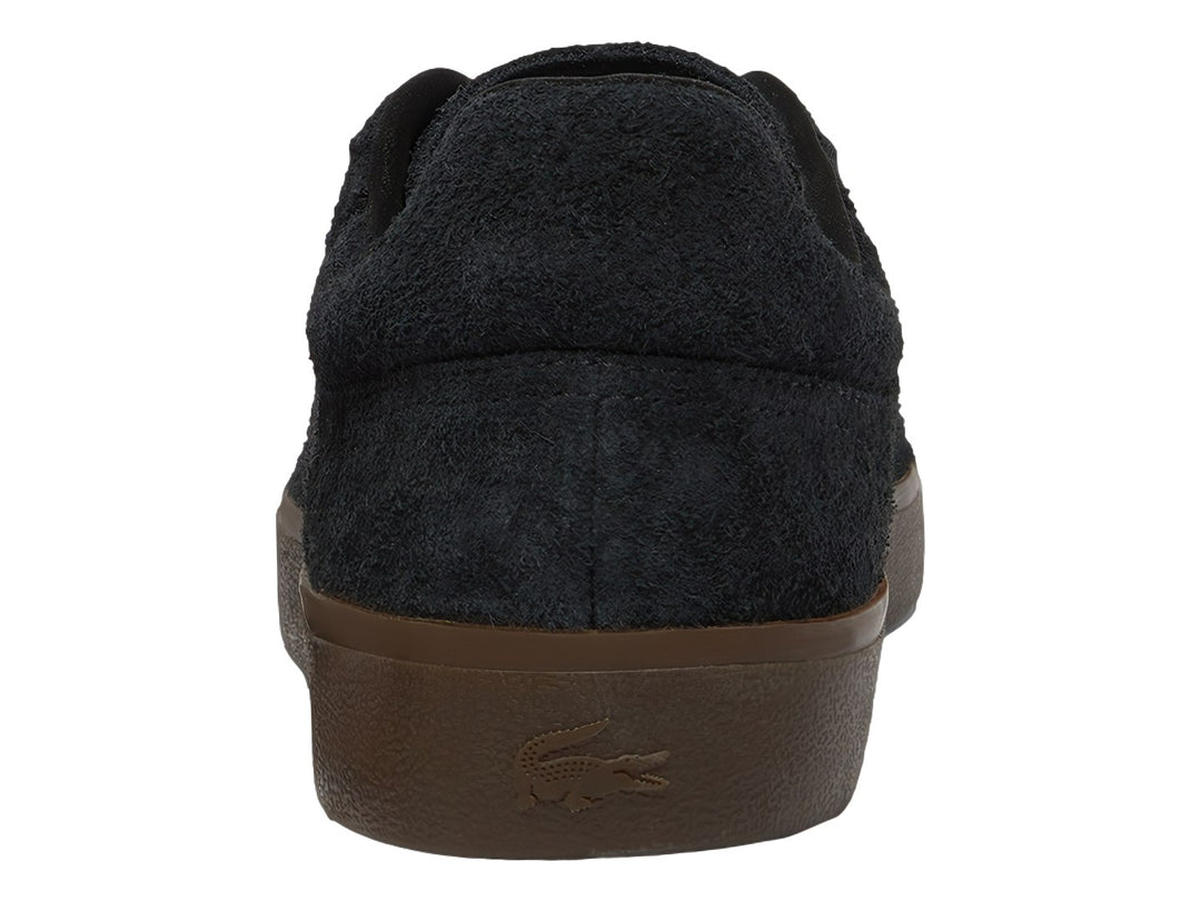 Tenis Lacoste de gamuza color negro con suela café y logotipo dorado en el lateral.
