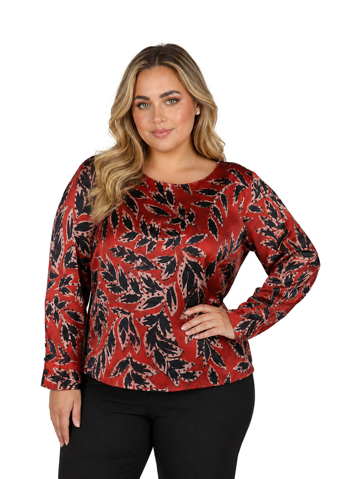 Mujer vistiendo una blusa roja con estampado de hojas negras y manga larga.