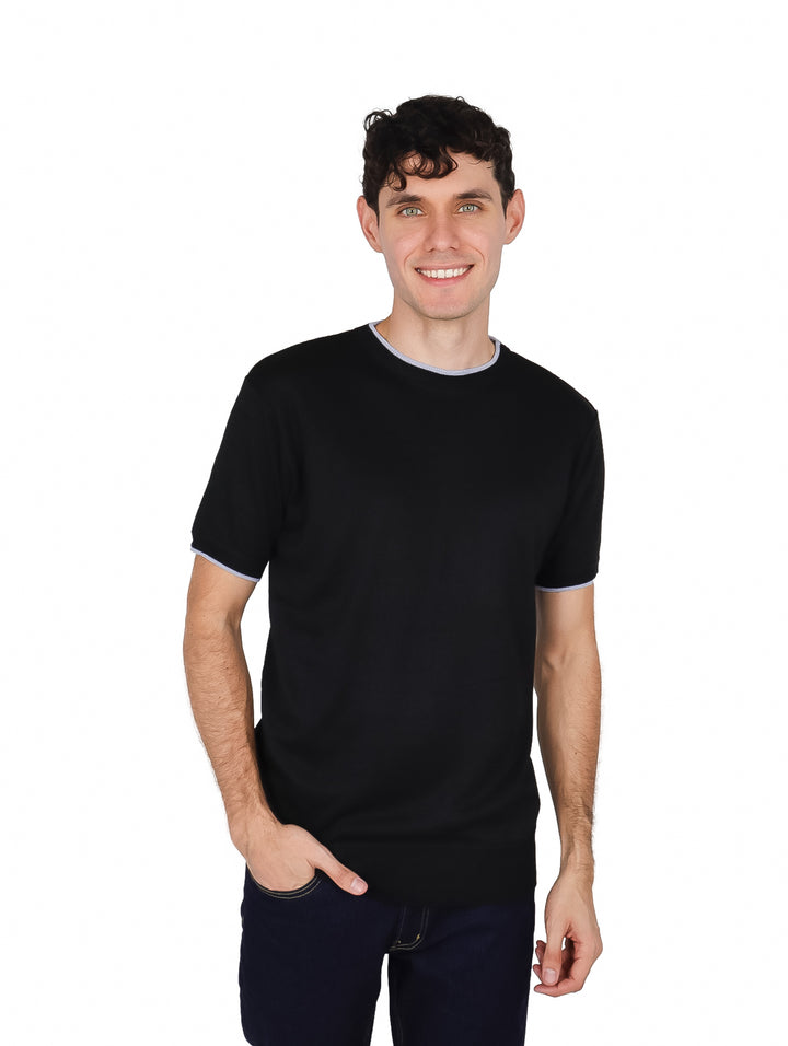 Hombre vistiendo una camiseta negra de manga corta con detalles en gris en el cuello y los bordes de las mangas.