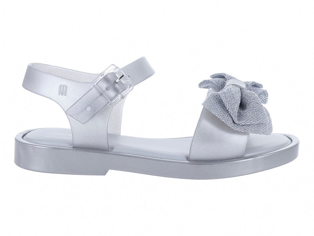 Sandalia plateada para niña con moño decorativo y correa ajustable.