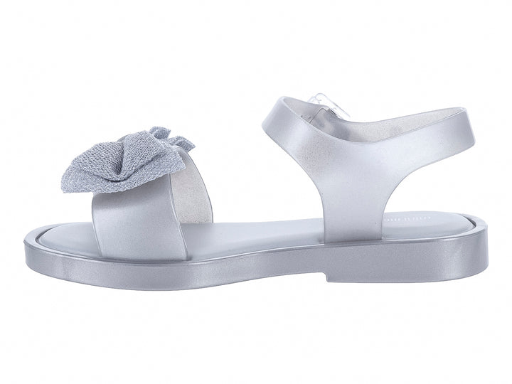 Sandalia plateada para niña con moño decorativo y correa ajustable.