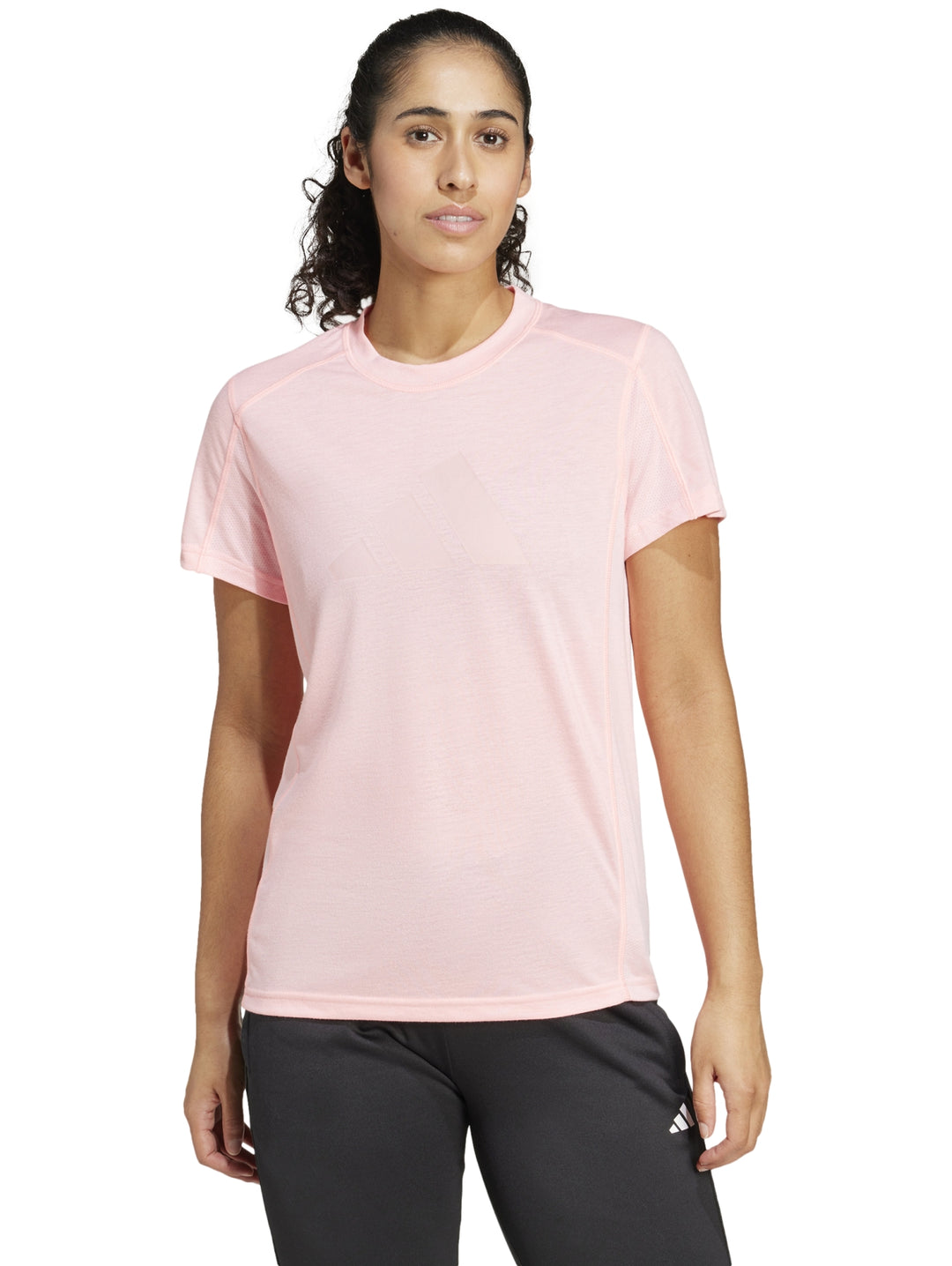 Mujer vistiendo playera de entrenamiento Adidas en color rosa claro con cuello redondo y manga corta.