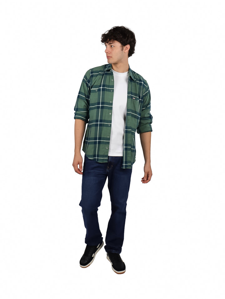 Hombre vistiendo una camisa de franela verde a cuadros con corte slim, combinada con camiseta blanca y jeans azules.