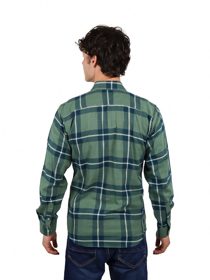 Hombre vistiendo una camisa de franela verde a cuadros con corte slim, combinada con camiseta blanca y jeans azules.