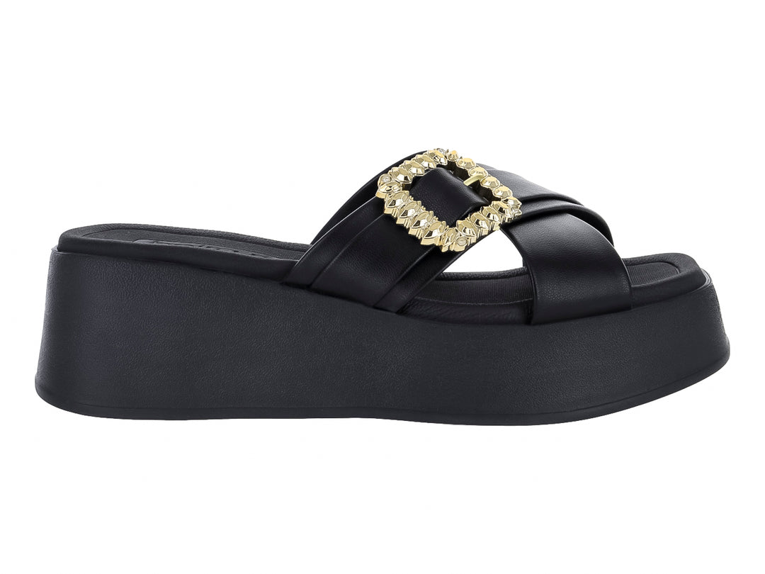 Sandalia negra de plataforma con hebilla decorativa dorada brillante en la parte superior.