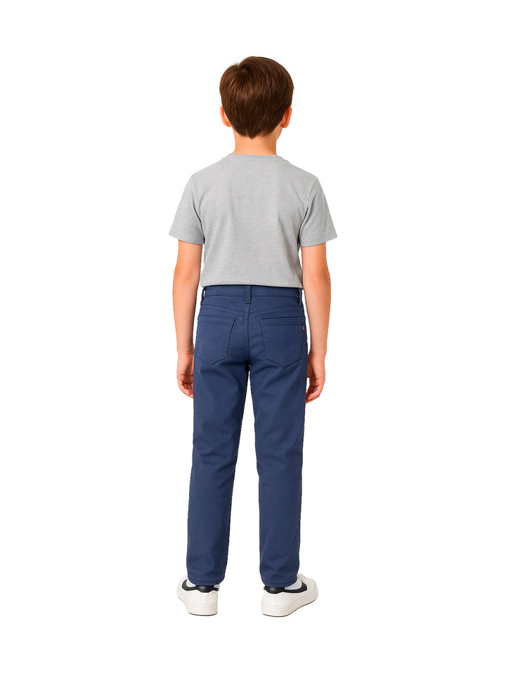 Niño vistiendo un pantalón color marino de corte recto y camiseta gris sobre fondo blanco.