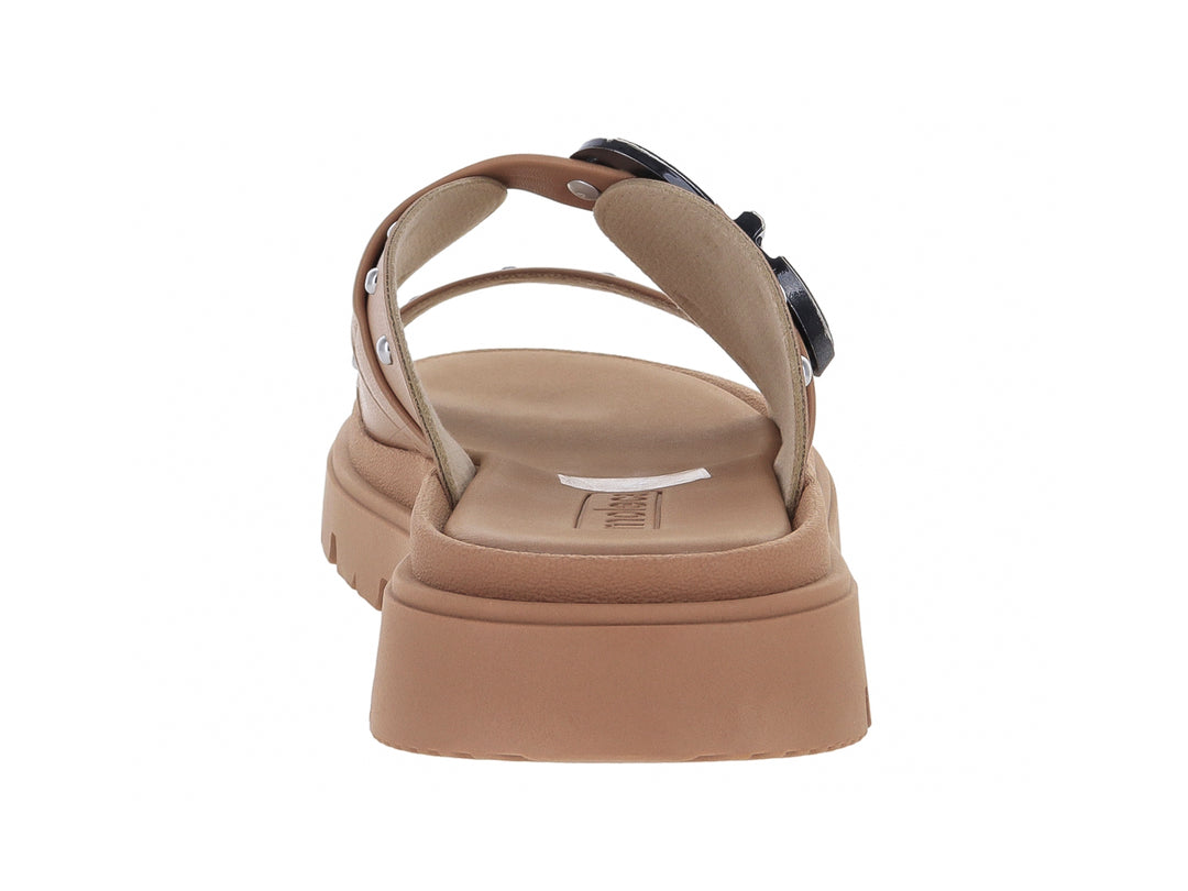 Sandalia slide color nude con suela de plataforma chunky, hebilla plateada y detalles de estoperoles.
