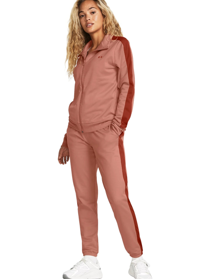 Conjunto deportivo Under Armour rosa con franjas laterales rojas, compuesto por chaqueta y pantalón.