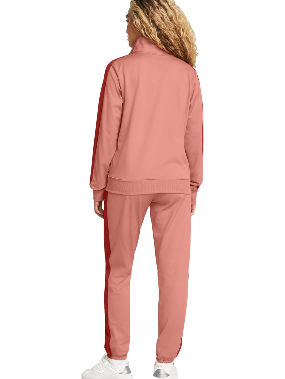 Conjunto deportivo Under Armour rosa con franjas laterales rojas, compuesto por chaqueta y pantalón.