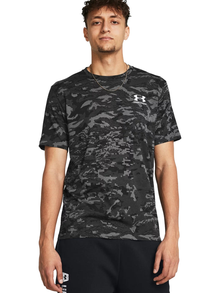 Hombre vistiendo camiseta deportiva Under Armour con estampado de camuflaje en tonos gris y negro.