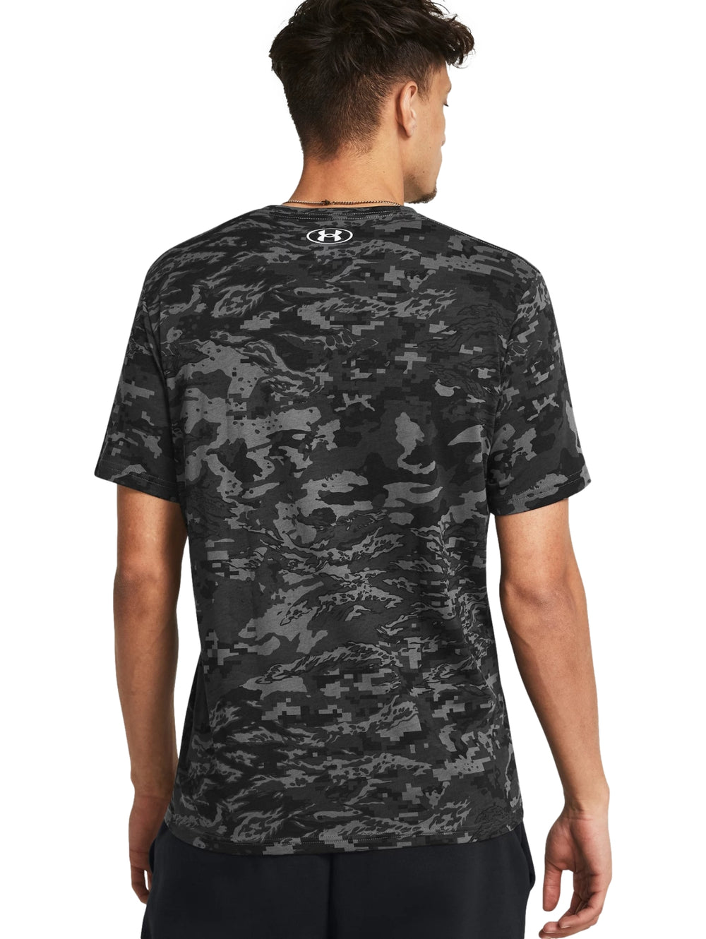 Hombre vistiendo camiseta deportiva Under Armour con estampado de camuflaje en tonos gris y negro.