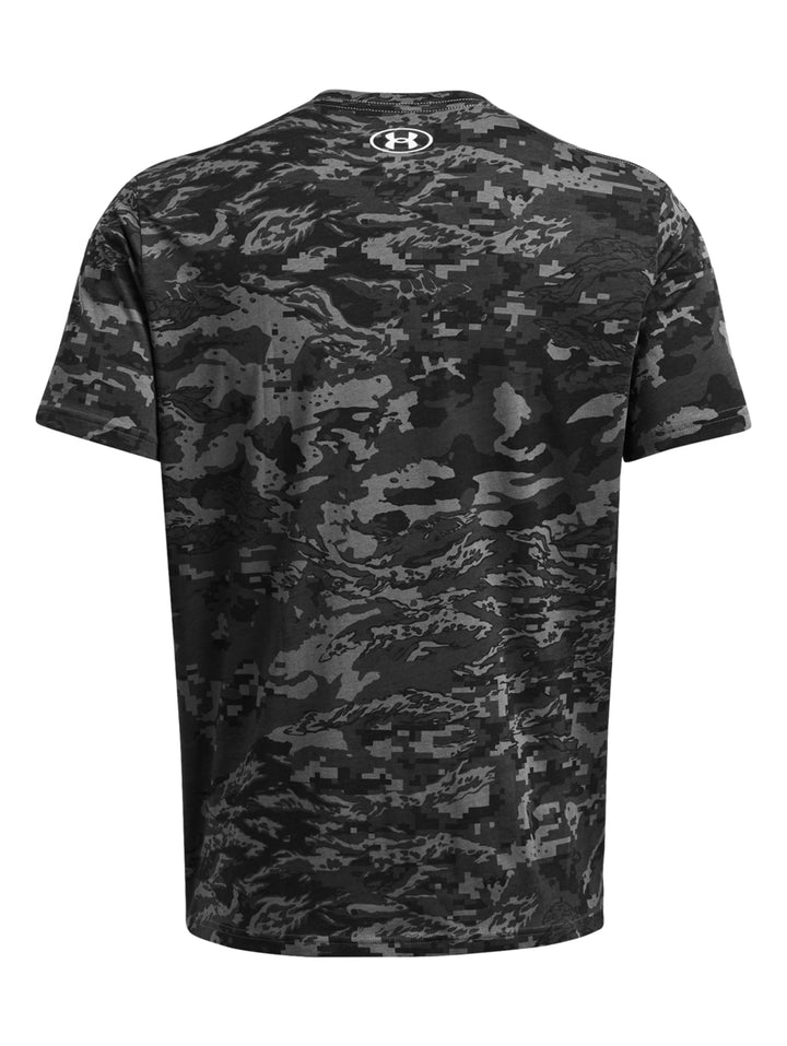 Hombre vistiendo camiseta deportiva Under Armour con estampado de camuflaje en tonos gris y negro.