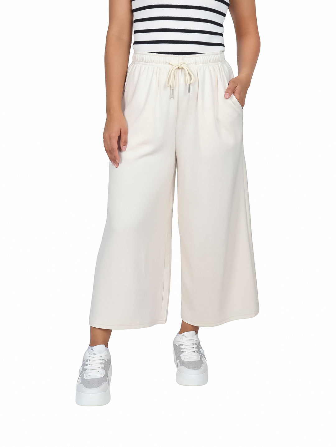 Mujer vistiendo pantalones culotte color beige con cintura elástica y bolsillos laterales.