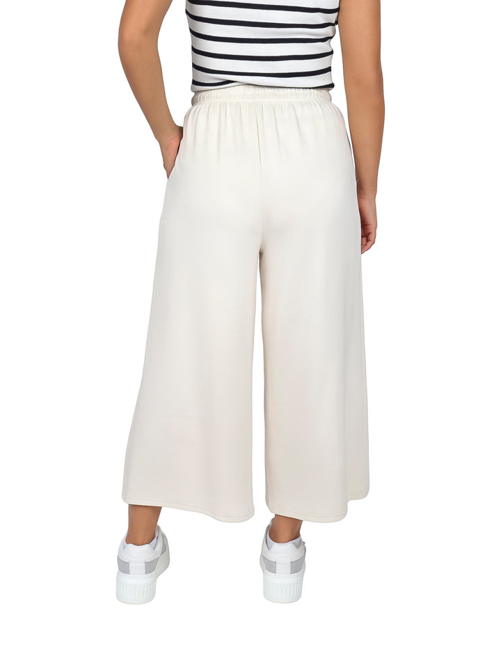 Mujer vistiendo pantalones culotte color beige con cintura elástica y bolsillos laterales.