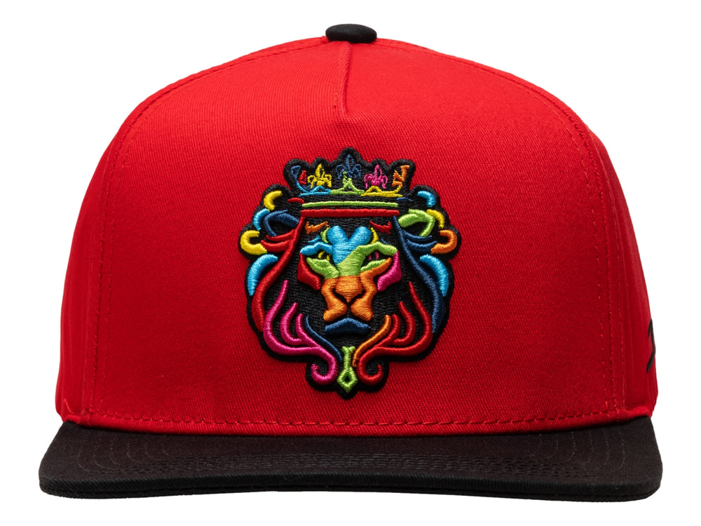 Gorra snapback roja con visera plana negra y bordado colorido de un león con corona en el frente.