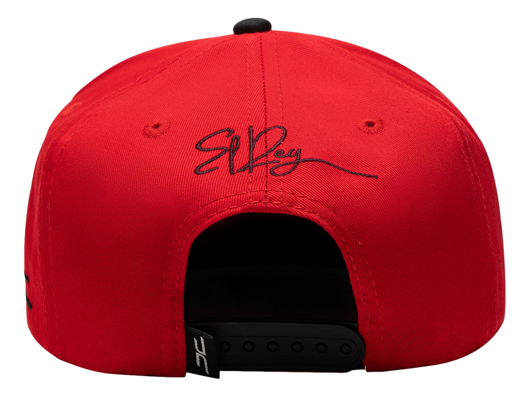 Gorra snapback roja con visera plana negra y bordado colorido de un león con corona en el frente.
