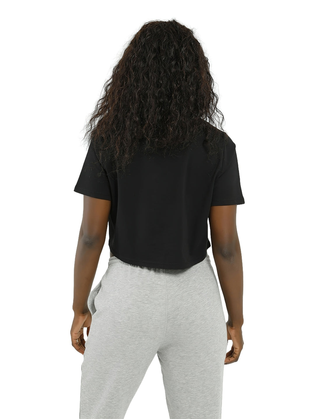 Mujer vistiendo una camiseta crop top negra de Reebok con logotipo blanco grande en el pecho.