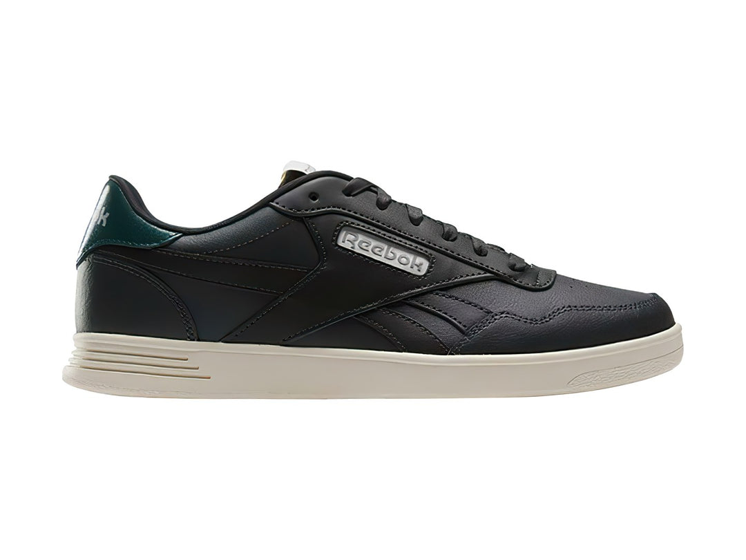Tenis Reebok Court Advance color gris oscuro con detalle verde en el talón y suela blanca.