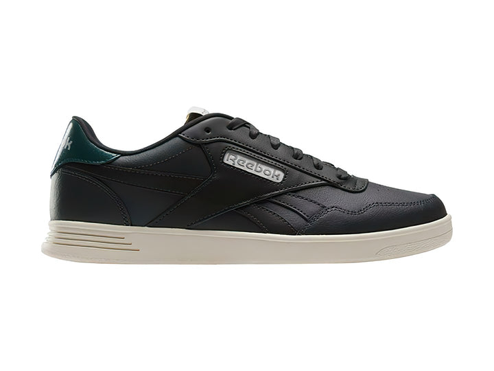 Tenis Reebok Court Advance color gris oscuro con detalle verde en el talón y suela blanca.