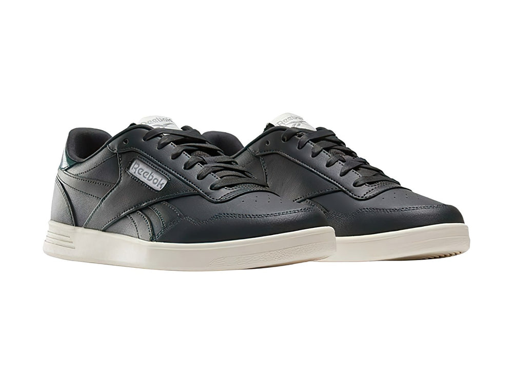 Tenis Reebok Court Advance color gris oscuro con detalle verde en el talón y suela blanca.