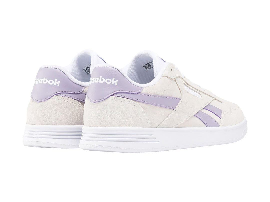 Tenis Reebok Court Advance color gris con detalles en lila y suela blanca.