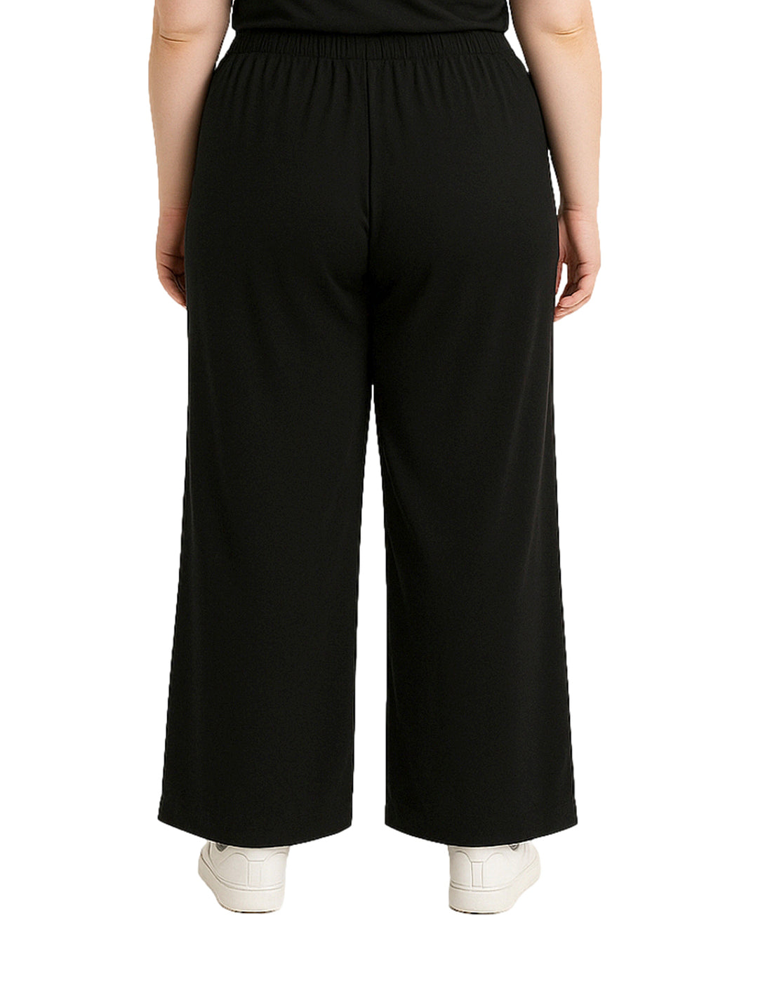 Mujer vistiendo pantalón recto ancho de color negro con pretina elástica y tenis blancos.