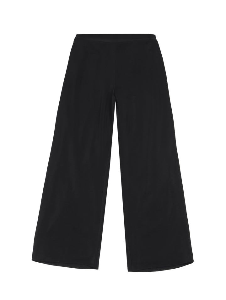 Mujer vistiendo pantalón recto ancho de color negro con pretina elástica y tenis blancos.