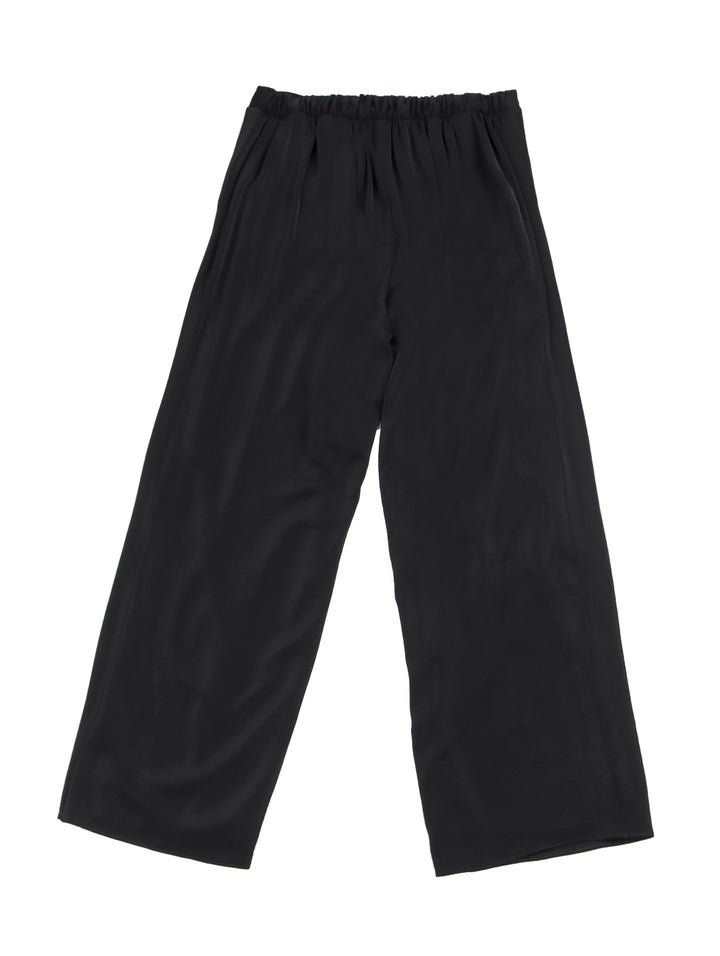 Mujer vistiendo pantalón recto ancho de color negro con pretina elástica y tenis blancos.