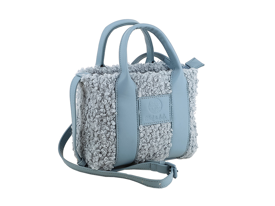 Bolso color cerúleo con textura de borrego, asas superiores y correa ajustable.