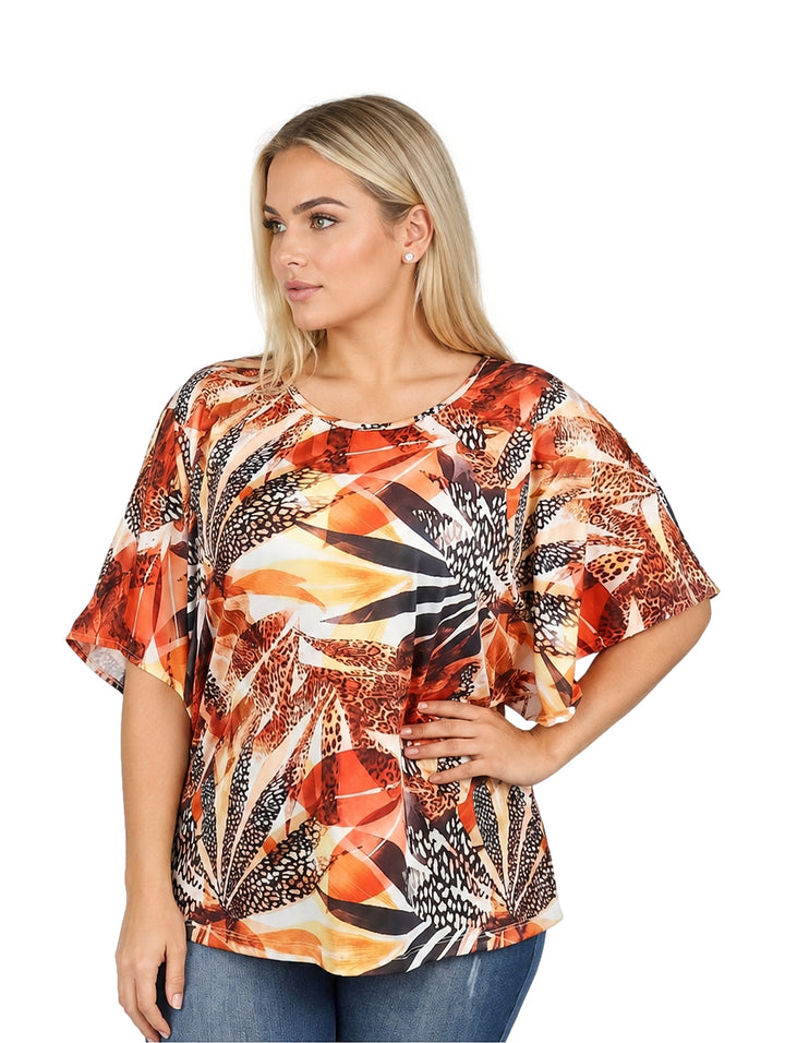 Mujer vistiendo blusa holgada de manga corta con estampado multicolor en tonos naranja y amarillo.