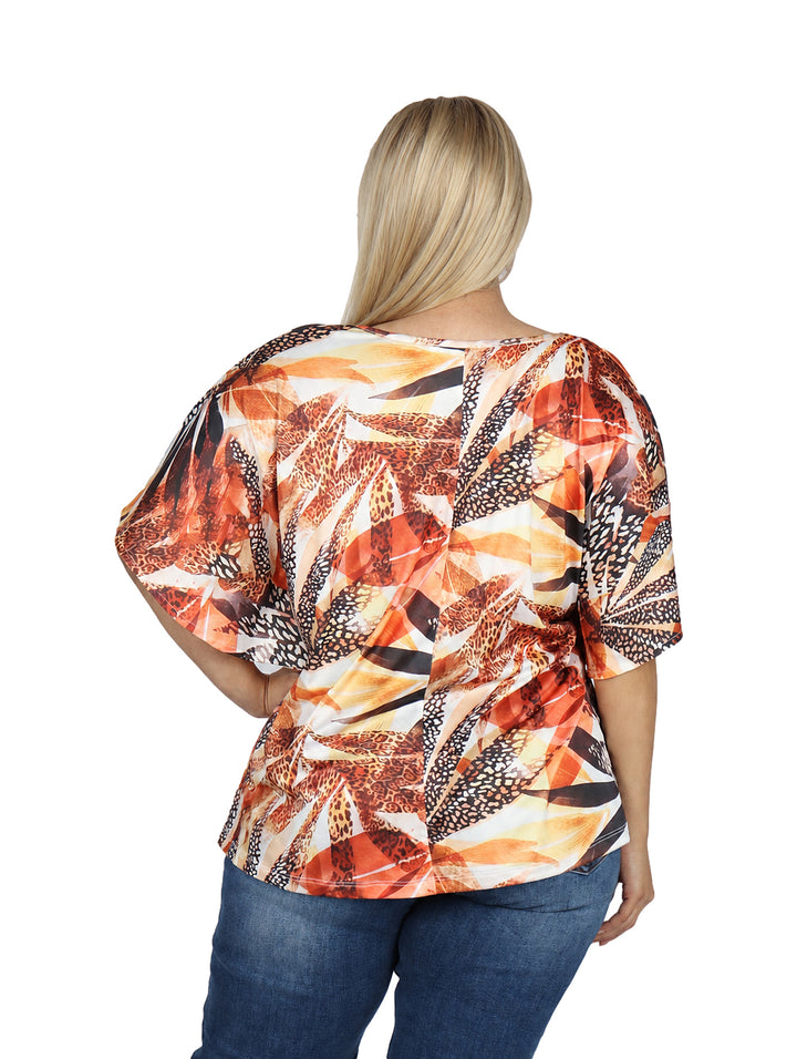 Mujer vistiendo blusa holgada de manga corta con estampado multicolor en tonos naranja y amarillo.
