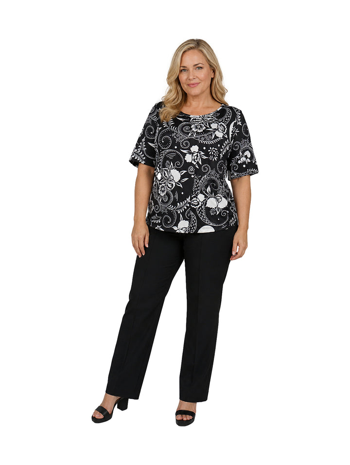 Mujer vistiendo blusa de manga corta color negro con estampado floral blanco y cuello redondo.