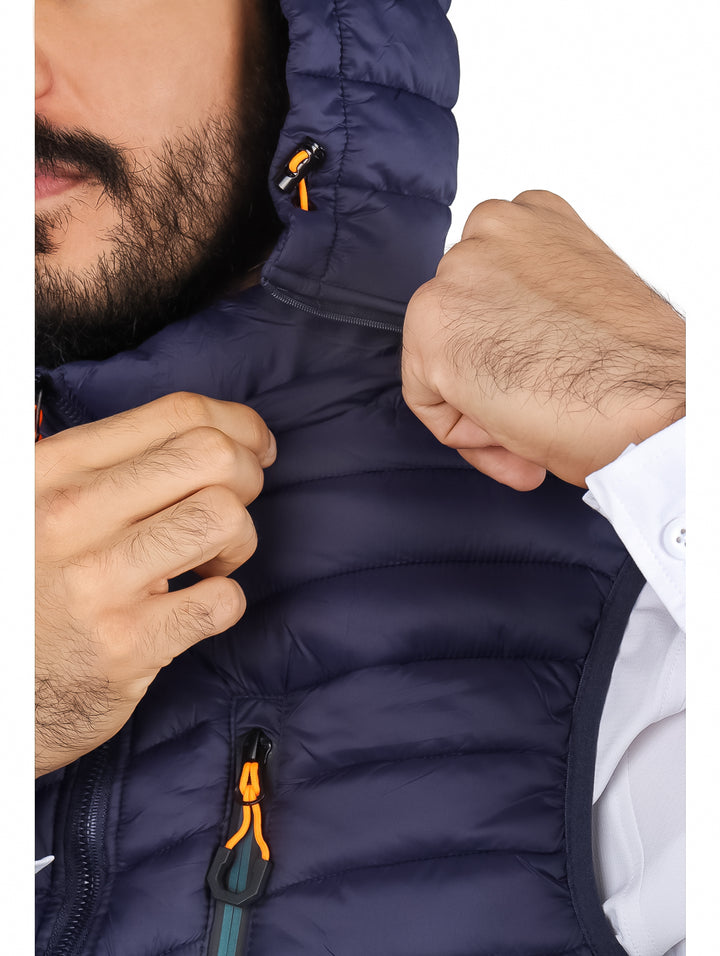 Hombre vistiendo un chaleco acolchado color navy con gorro y detalles en naranja.