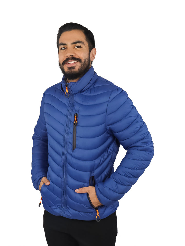 Hombre vistiendo chamarra acolchada color azul con gorro y detalles en naranja.