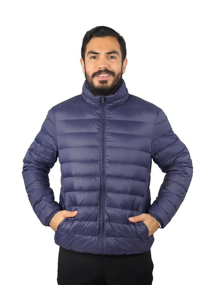 Hombre vistiendo una chamarra acolchada de pluma color azul marino con cuello alto y bolsillos laterales.
