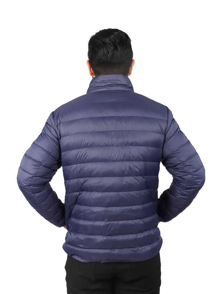 Hombre vistiendo una chamarra acolchada de pluma color azul marino con cuello alto y bolsillos laterales.