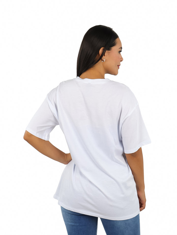 Mujer vistiendo camiseta oversize blanca con estampado gráfico en color verde de Cowboy Carter.