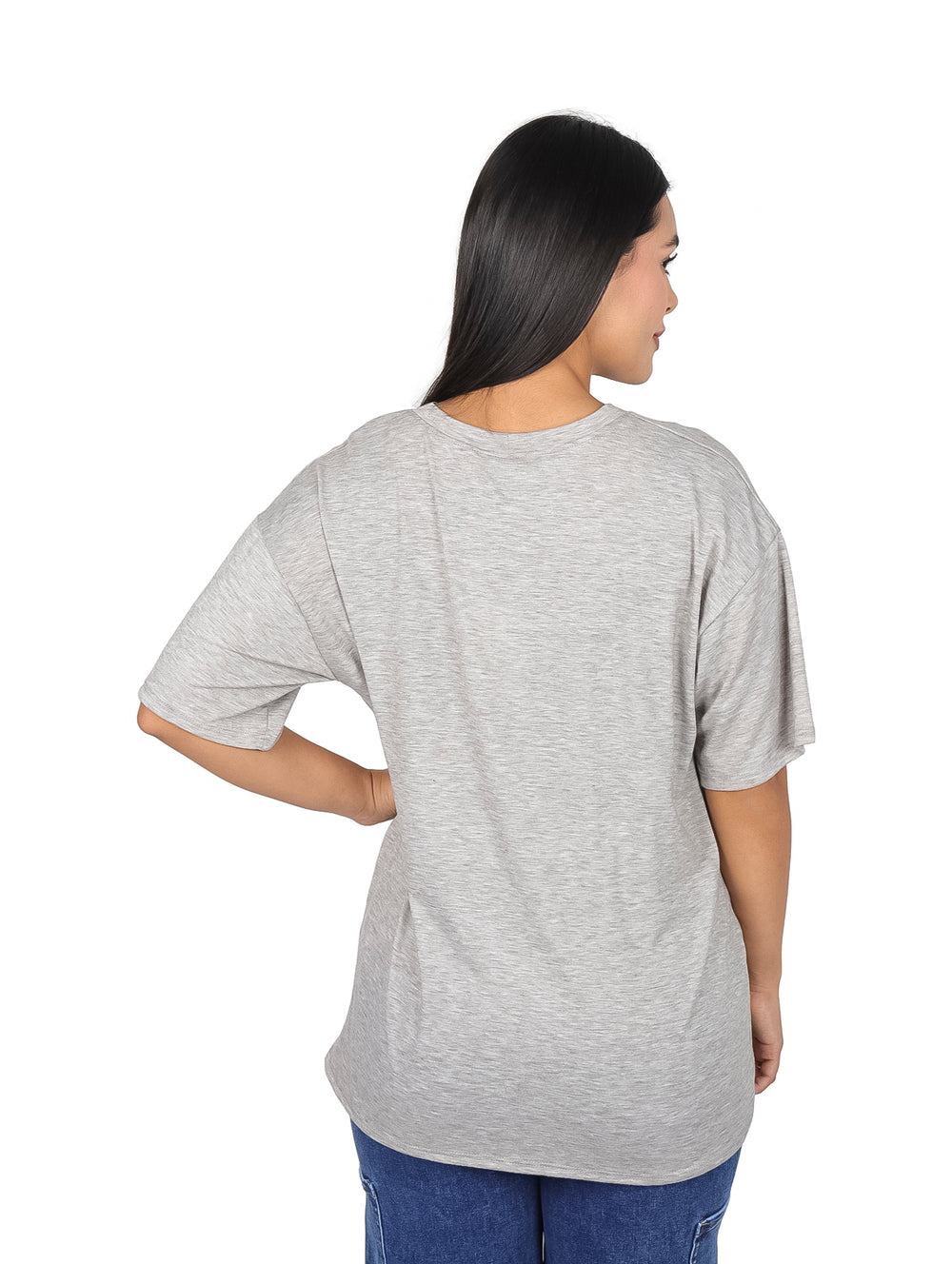 Mujer vistiendo camiseta oversize color gris con estampado gráfico de carreras en el pecho.
