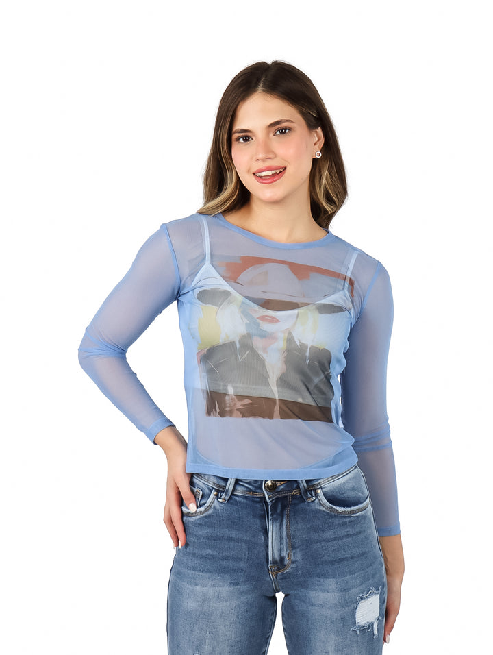 Mujer vistiendo blusa azul transparente de manga larga con estampado gráfico frontal y jeans azules.